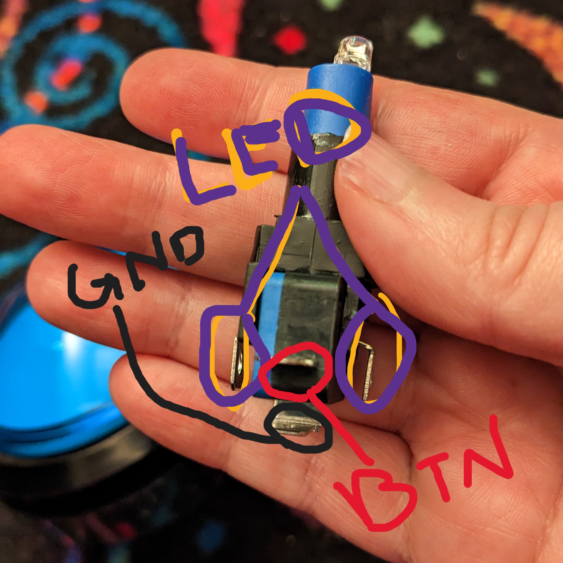 Photo of my hand holding the microswitch/LED, with terminals labelled LED, BTN, and GND